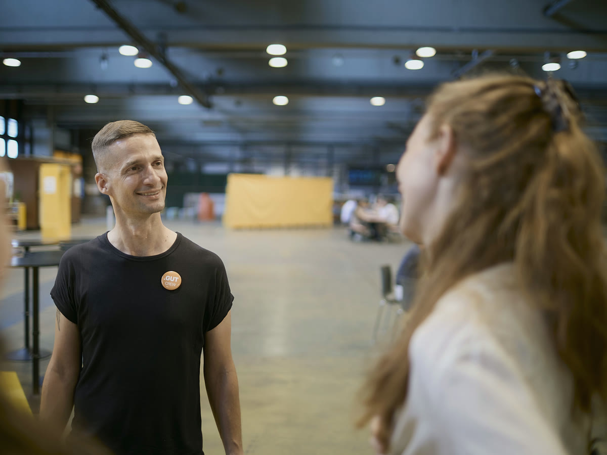 Marc Bernath lächelnd im Gespräch mit einer Besucherin in der Halle des Innovationszentrums Berlin TXL
